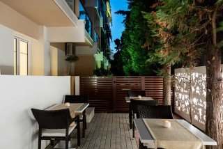 gallery galaxias hotel outdoor lounge area with many tables and chairs surrounded by a garden